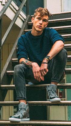 a young man sitting on top of a stair case