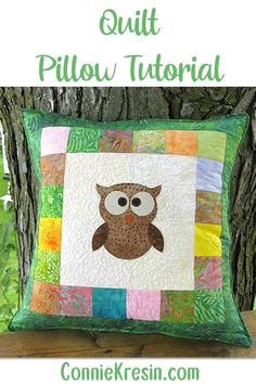 an owl pillow sitting on top of a wooden bench next to a tree with the words quilt