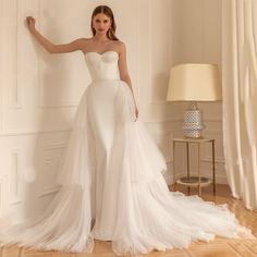 a woman in a white wedding dress standing next to a wall