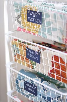 three baskets filled with fabric and labels on them