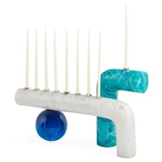 a white and blue sculpture with candles on it's back end in front of a white background