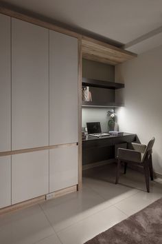 a room with a chair, desk and cabinets on the wall next to a window