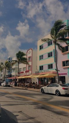 cars are driving down the street in front of colorful buildings and palm trees on a sunny day