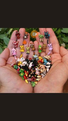 someone is holding their hand full of tiny figurines in front of some plants