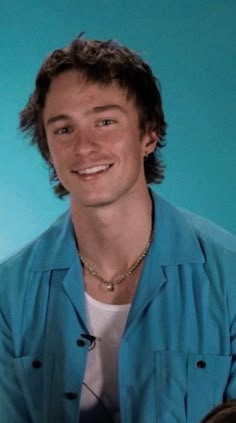 a young man smiling and wearing a blue shirt