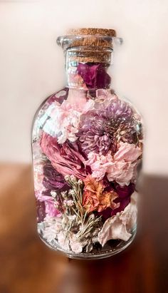 a glass bottle filled with flowers on top of a wooden table