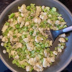 a pan filled with cauliflower and broccoli on top of a stove