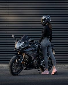 a woman standing next to a parked motorcycle