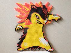 a cross stitch pokemon brooch hanging on a wall in front of a white wall