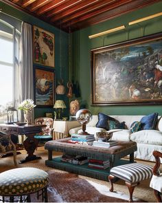 a living room filled with lots of furniture and paintings on the wall above it's windows