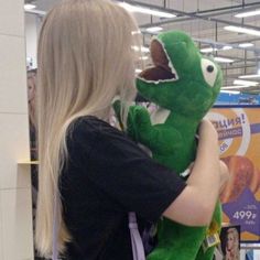 a woman holding a green stuffed animal in her arms