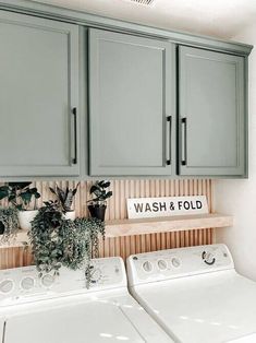 a washer and dryer in a laundry room with green cabinetry on the wall