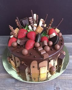 a chocolate cake topped with strawberries, chocolate bars and other toppings on a green plate