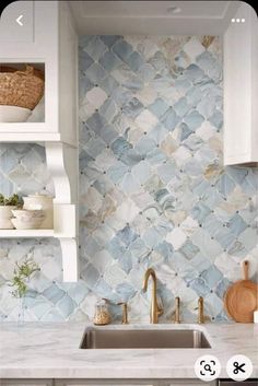 a kitchen with blue and white tiles on the wall, sink and shelving above it