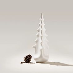 a white vase sitting next to a pine cone