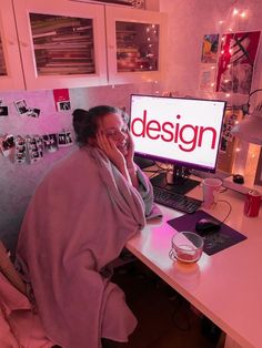 a woman sitting in front of a computer desk with a blanket over her head and the word design on it