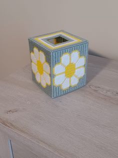 a small blue and yellow box sitting on top of a wooden table next to a white wall