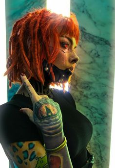 a woman with red hair is talking on her cell phone and has tattoos on her arm