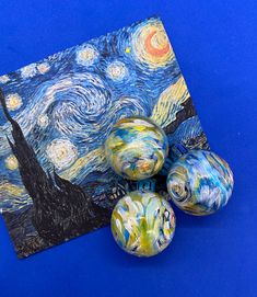 three marbles sitting on top of a blue surface next to an image of the starry night