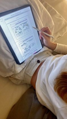 a person laying in bed with a laptop on their lap and holding a pair of scissors