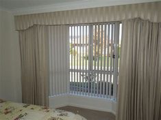 a bed sitting in a bedroom next to a window with blinds on top of it