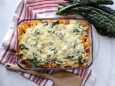 a casserole dish with spinach, cheese and sauce in it on a red and white towel