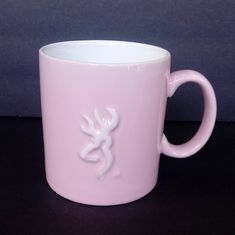 a pink coffee mug with a white deer on it's side and the bottom part of its cup is shown