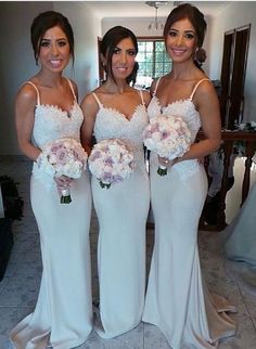 three beautiful women standing next to each other holding bouquets in front of a mirror