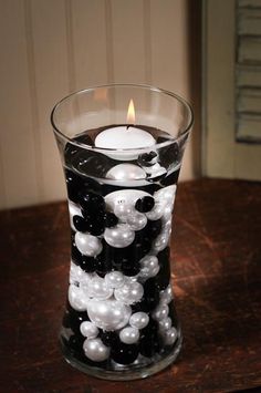 a candle that is sitting in a glass with some beads on the inside of it