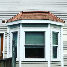 a white house with a red roof and a brown window sill on the corner