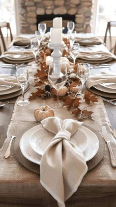 a table set for thanksgiving dinner with white plates and silverware, napkins and candles