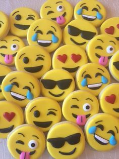 many yellow smiley face cookies with hearts and sunglasses on them, all decorated in different colors