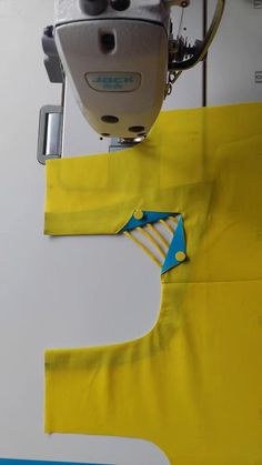 the sewing machine is working on the yellow piece of fabric that has been sewn