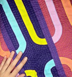 a person's hand on top of a colorful quilt