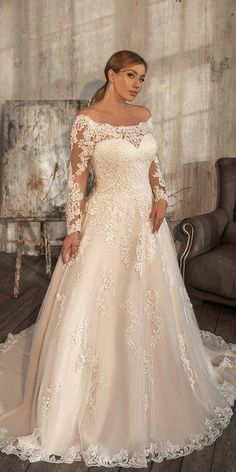 a woman in a wedding dress standing on a wooden floor next to a couch and chair