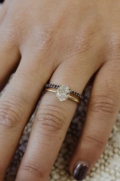 a woman's hand with a diamond ring on top of her finger and the other hand holding an engagement ring