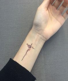 a woman's wrist with a small cross tattoo on the left side of her arm