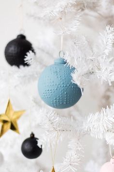 some ornaments are hanging from a white christmas tree