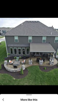 an aerial view of a large house with patio and covered in stone seating on the lawn