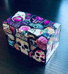 a colorful box with skulls on it sitting on top of a wooden table in front of a window