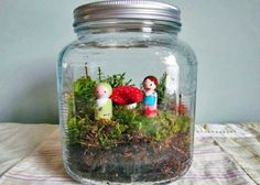 a jar filled with moss and little people