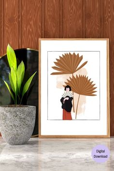 a potted plant sitting on top of a table next to a framed print with a woman holding a fan