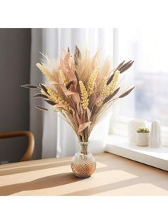 a vase filled with dried flowers on top of a wooden table