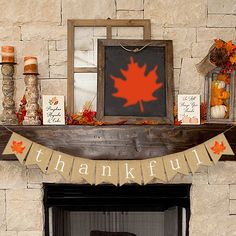 a mantel decorated with fall leaves, candles and other decorations for the thanksgiving mantle