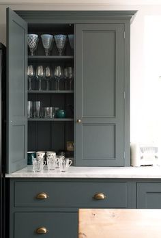 a kitchen with gray cupboards and glassware on the counter top in front of it