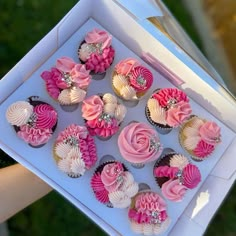 cupcakes with pink and white frosting in a box