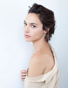 a woman with short hair is posing for the camera, wearing a off - white top