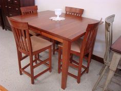 a wooden table with four chairs and a white cup on top of it in a room