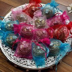 several chocolate candies are on a silver platter with blue and pink ribbons around them