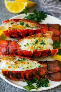 cooked lobsters on a plate with lemon wedges and parsley garnish